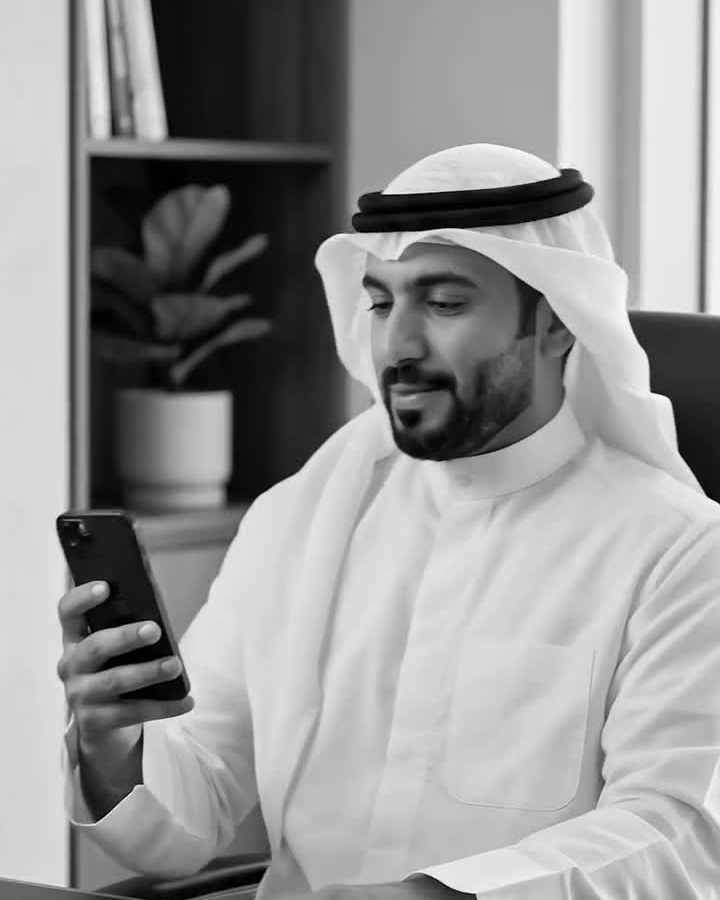 Black and white frame from an AI-generated property advert showing a man in traditional Gulf dress viewing a listing on his phone